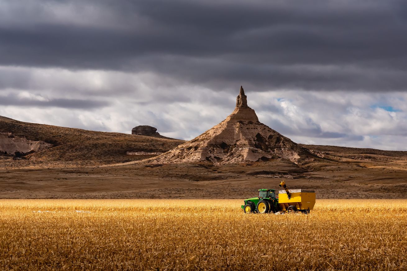 Tractor with combine on farm field and chimney rock
