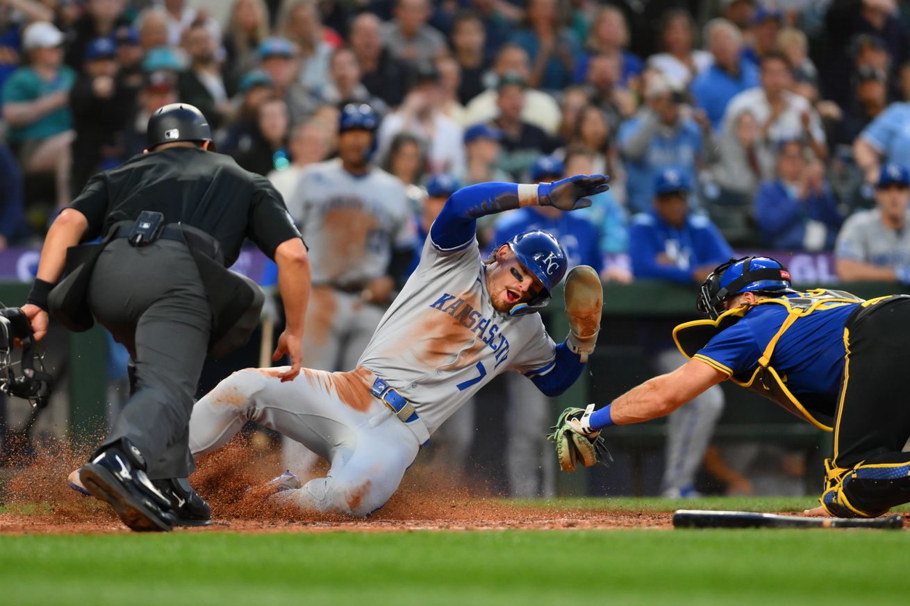 Bobby Witt Jr. performs an acrobatic slide at home plate to successfully avoid the tag of catcher Cal Raleigh