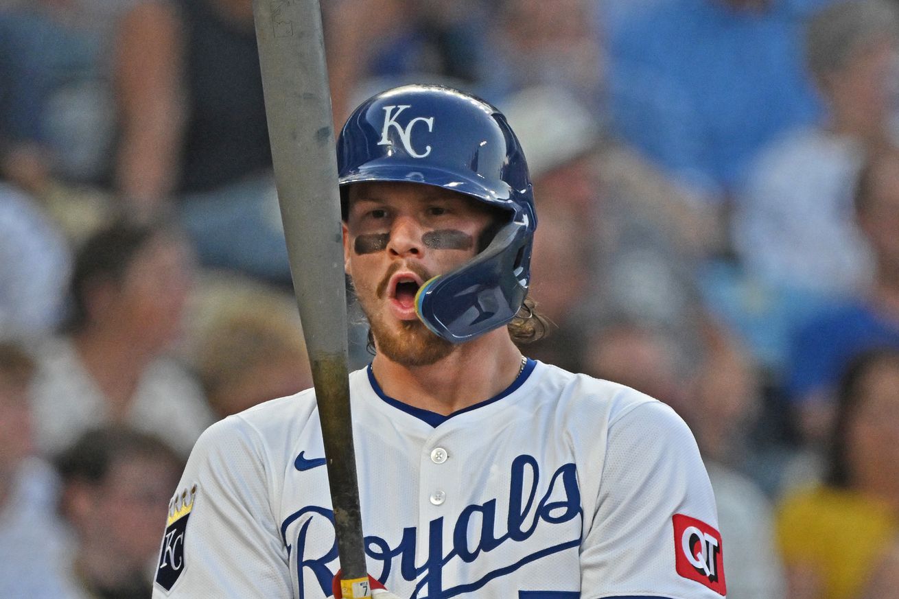 Baseball player Bobby Witt Jr takes a step back from the plate and raises his bat vertically in front of his face. He is breathing in.