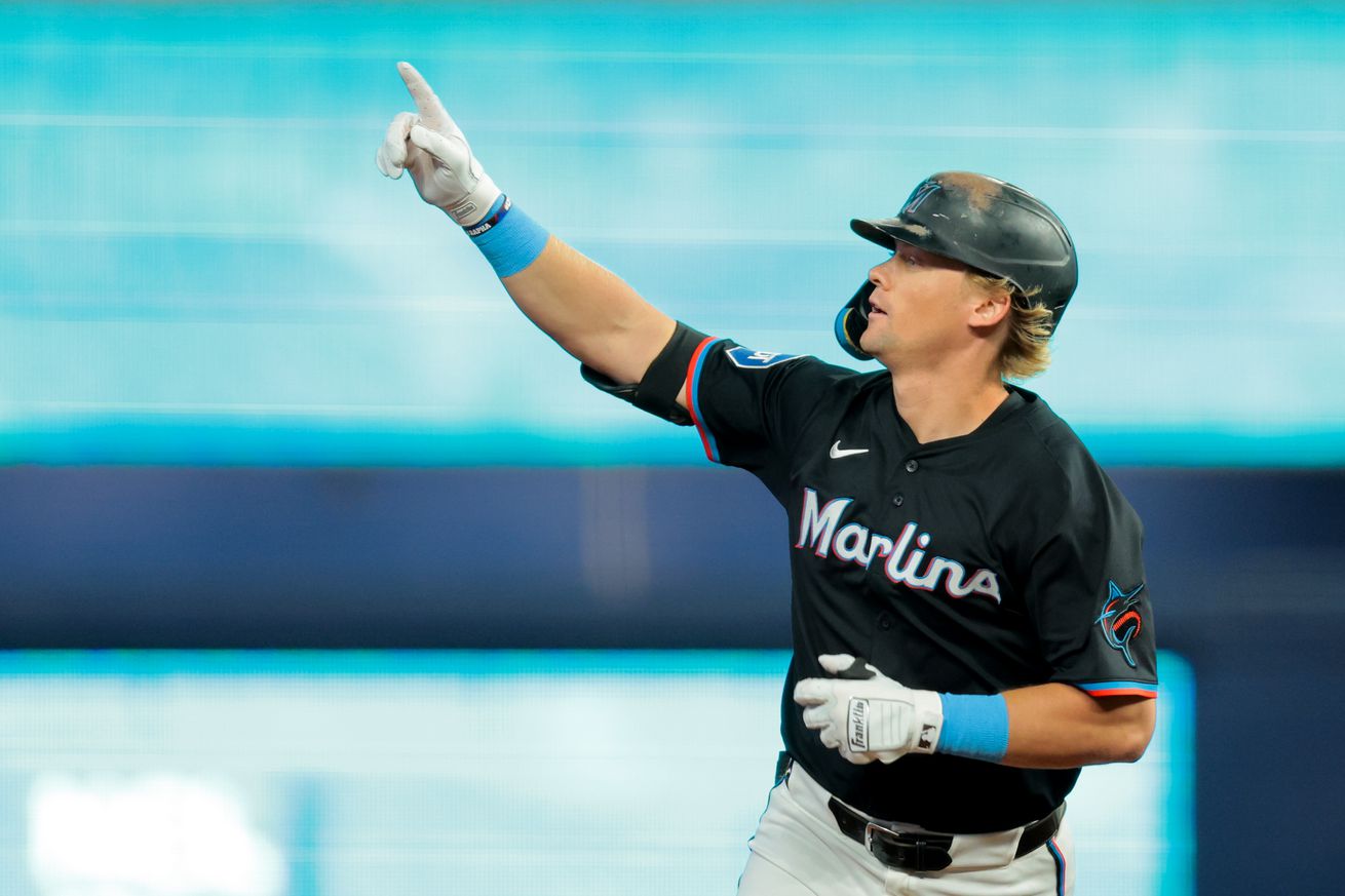Kyle Stowers raises his right arm to point at the crowd while running the bases after hitting a home run.
